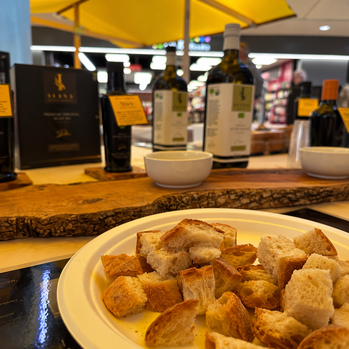 Brotstücke auf einem weissen Teller zur Olivenöl-Degustation vor dem Iline Organic Verkostungsstand.